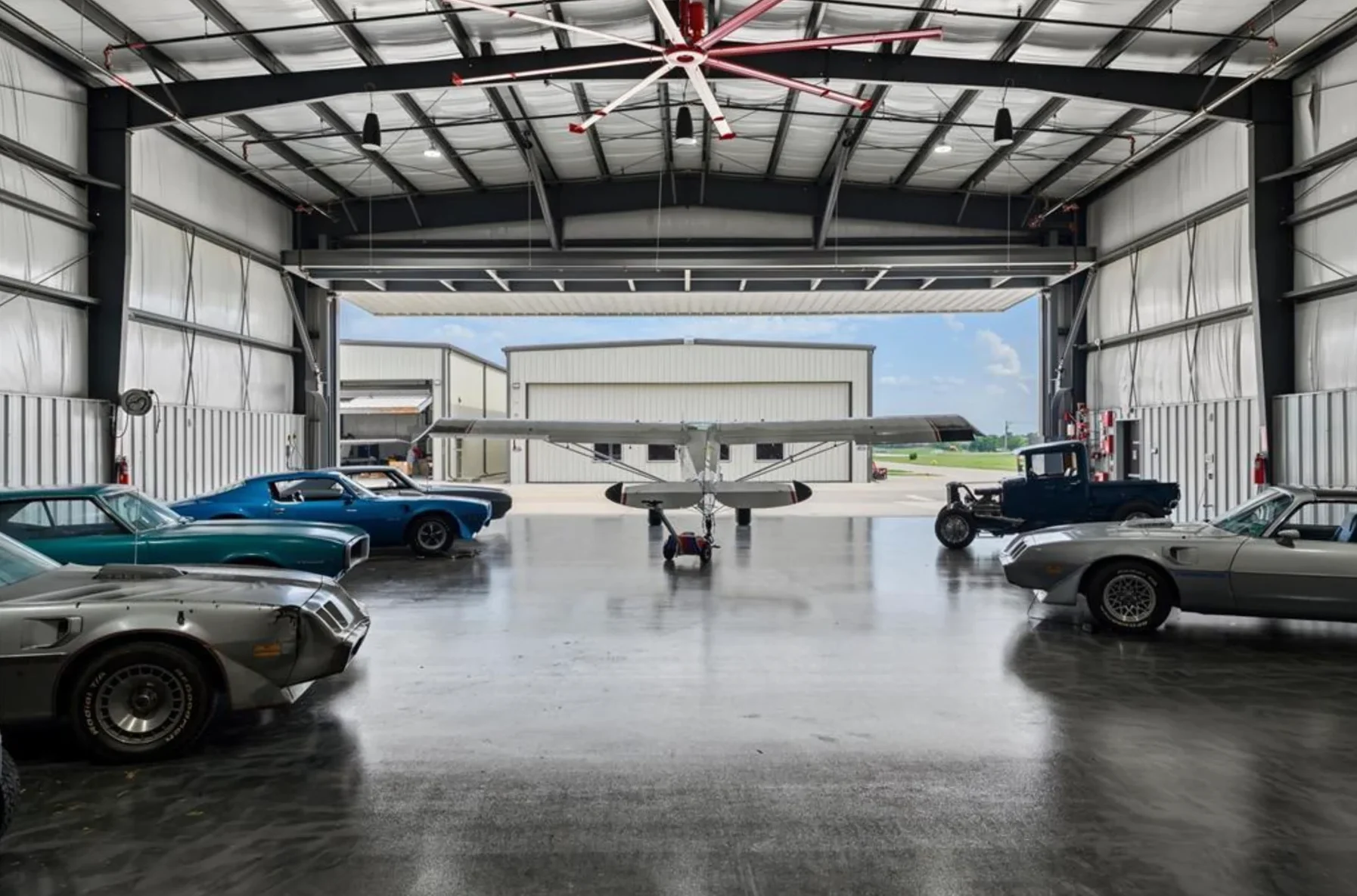 Representative finished aircraft hangar with airplane and collector cars